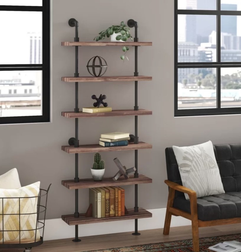 An iron ladder bookcase with six wooden shelves filled with books and decorative items