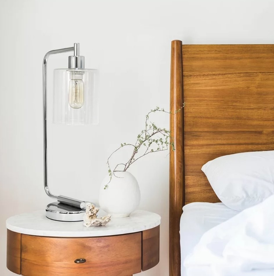 A chrome desk lamp that&#x27;s LED compatible atop a nightstand