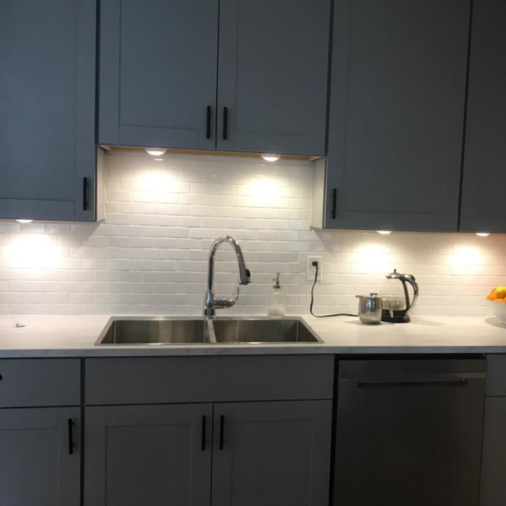 a reviewer image of a kitchen with the puck lights installed under the cabinets 