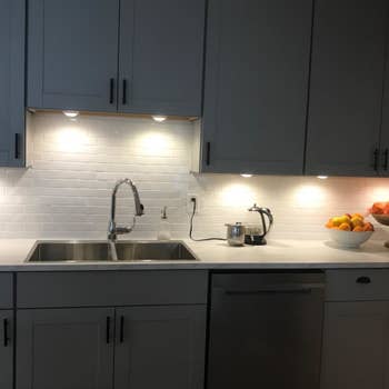 a reviewer image of a kitchen with the puck lights installed under the cabinets 