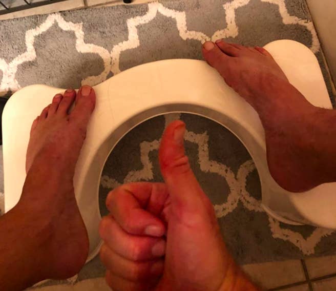 A customer review picture of their feet on the squatty potty around their toilet as they give a thumbs up