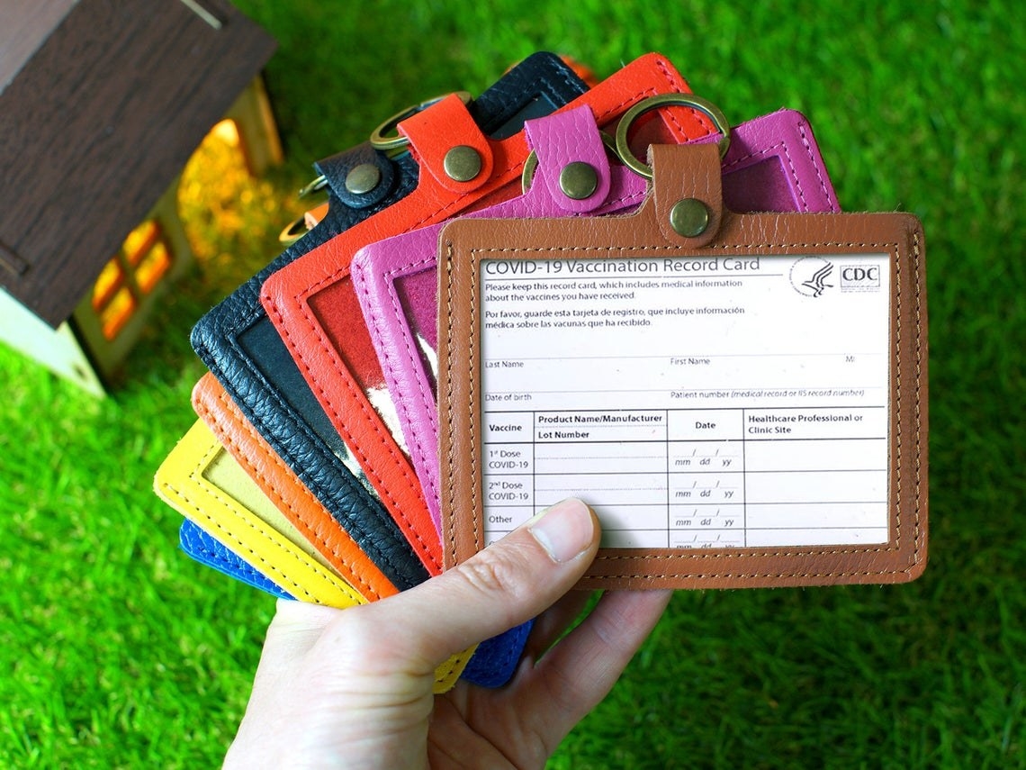 A person holding all the color options of the vaccine card holder