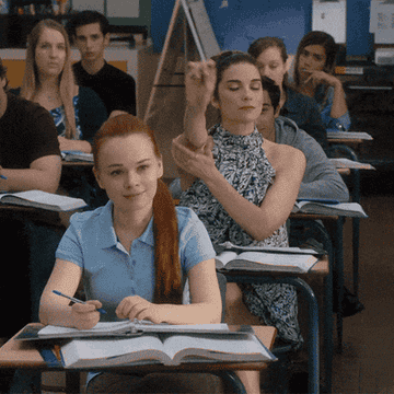 Alexis Rose puts her hand up in a high school class
