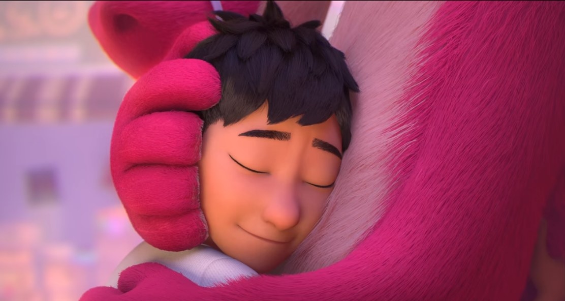 Boy hugging a pink dragon.