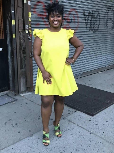 A reviewer wearing a yellow ruffle sleeve dress
