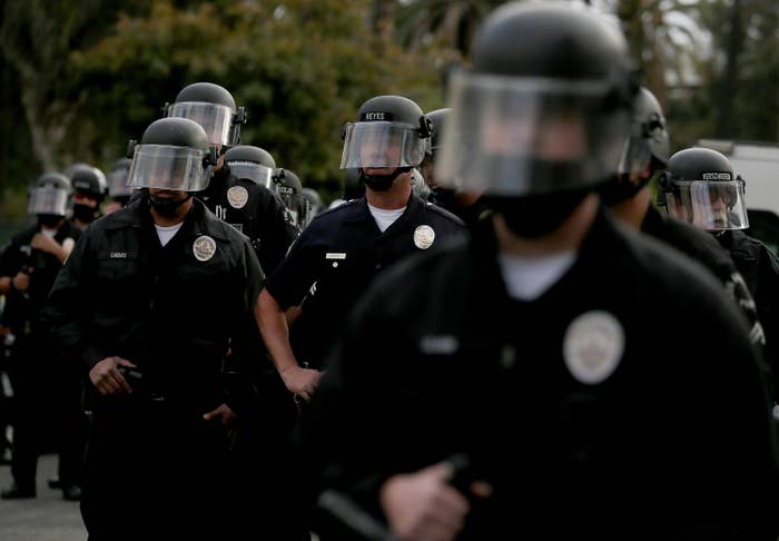 Police officers form a line on Lemoyne Street to block access to a camp of people experiencing homelessness in Echo Park