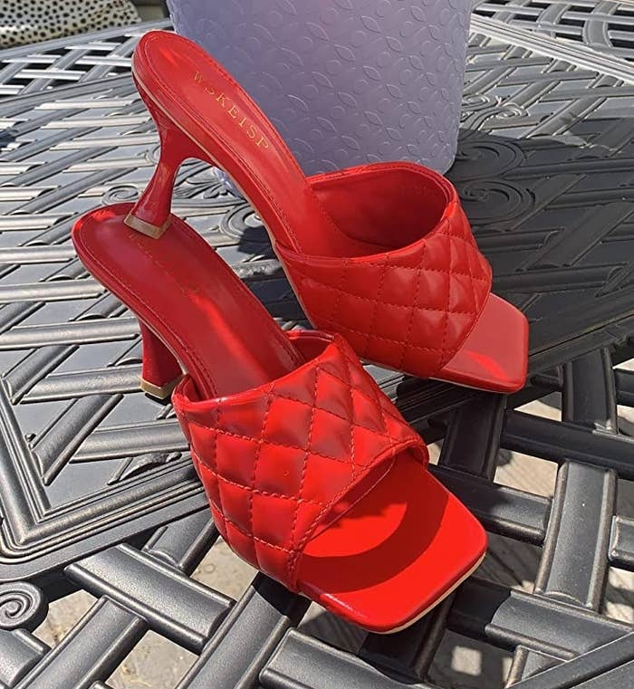 The bright red mules are square-shaped and have diamond pleated straps 
