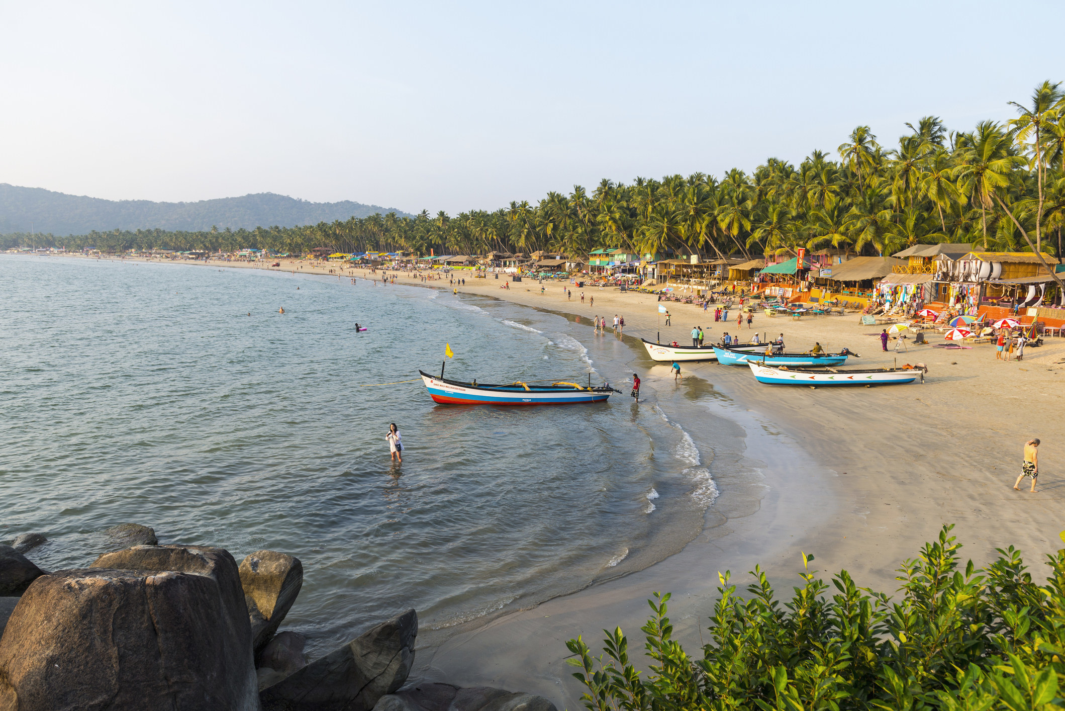 A beach with boats and people in Goa, India