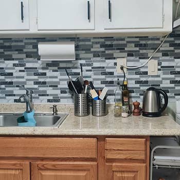 a reviewer photo of the kitchen with the peel and stick backsplash applied to the wall 