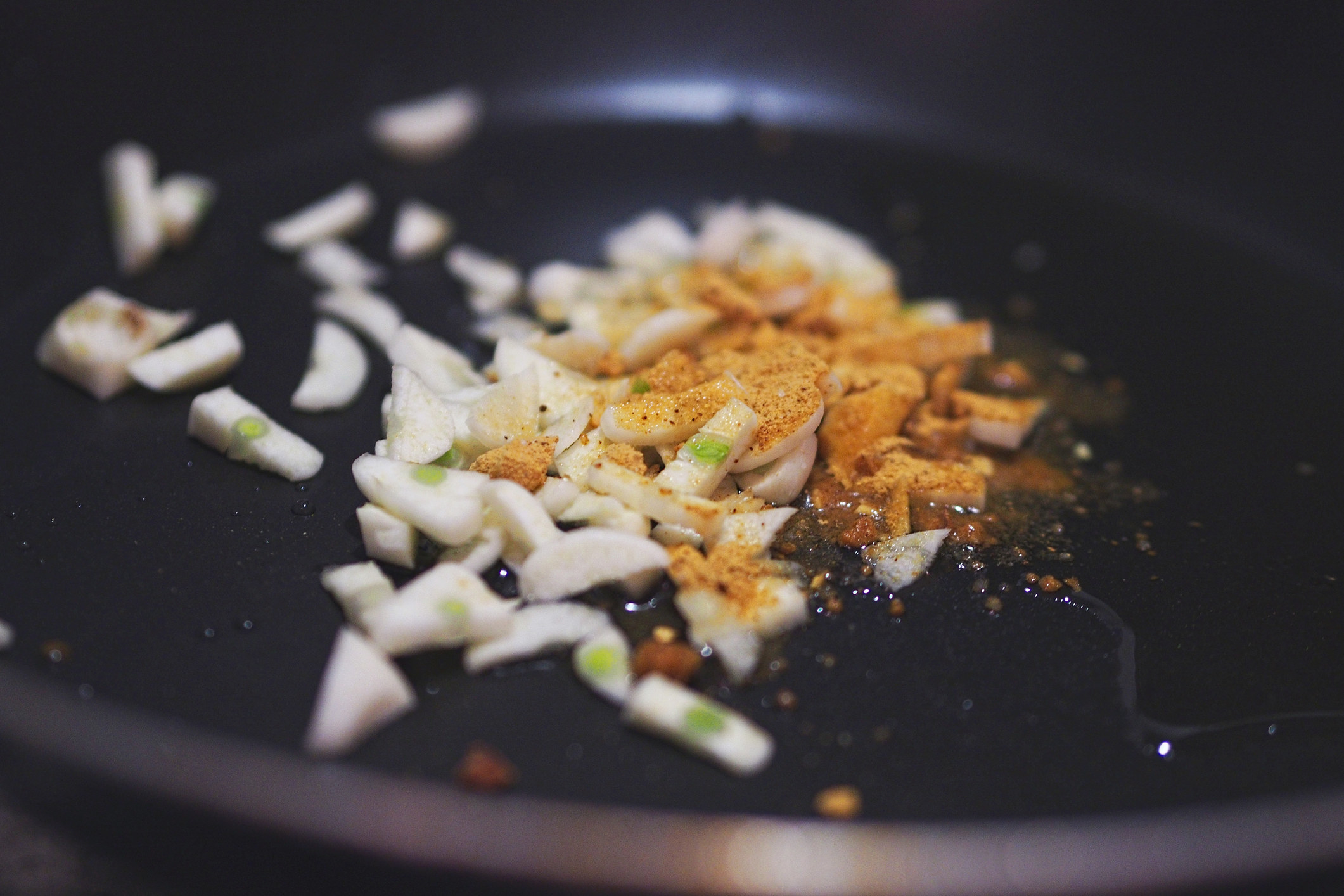 Garlic frying with spices in a pan.
