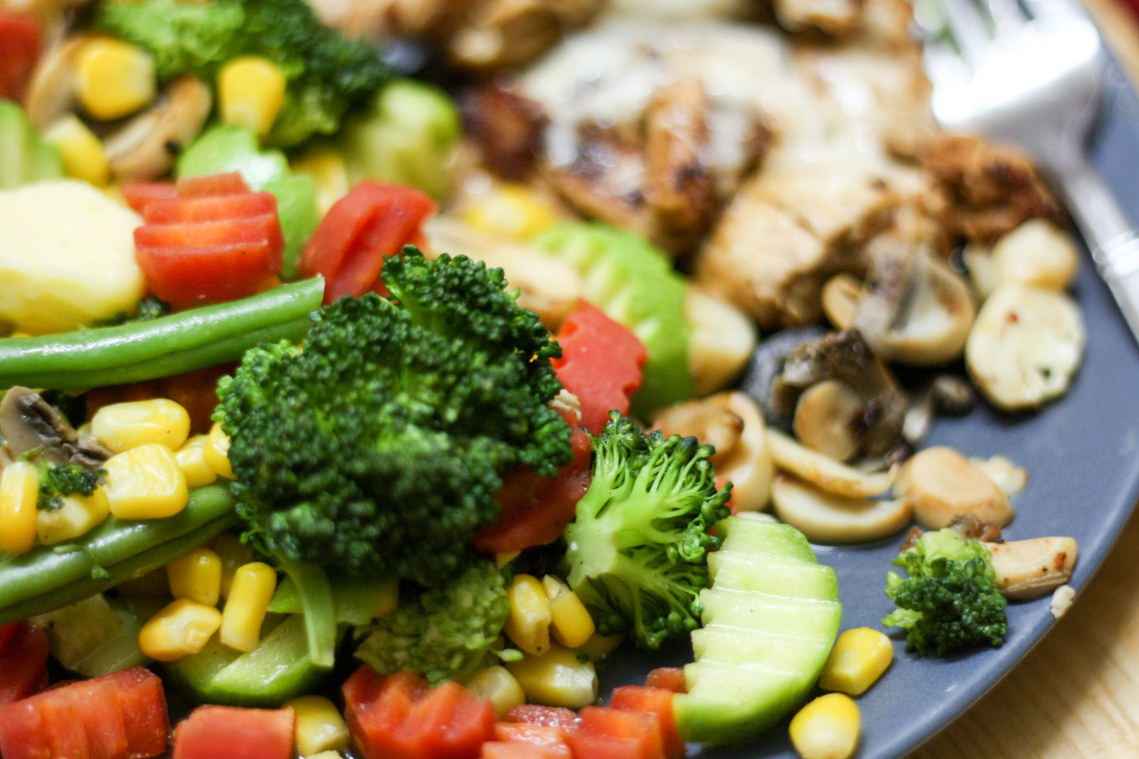 A plate of various steamed veggies like carrots, corn, and broccoli.