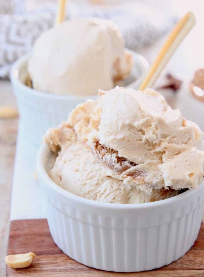 Scoops of peanut butter ice cream in a white bowl with a gold spoon.