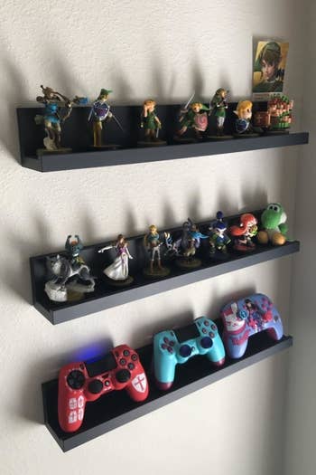 three Command ledges mounted on the wall with figurines and gaming controller on it 