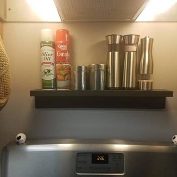 a Command ledge mounted on the wall over a stove with cooking supplies on it 