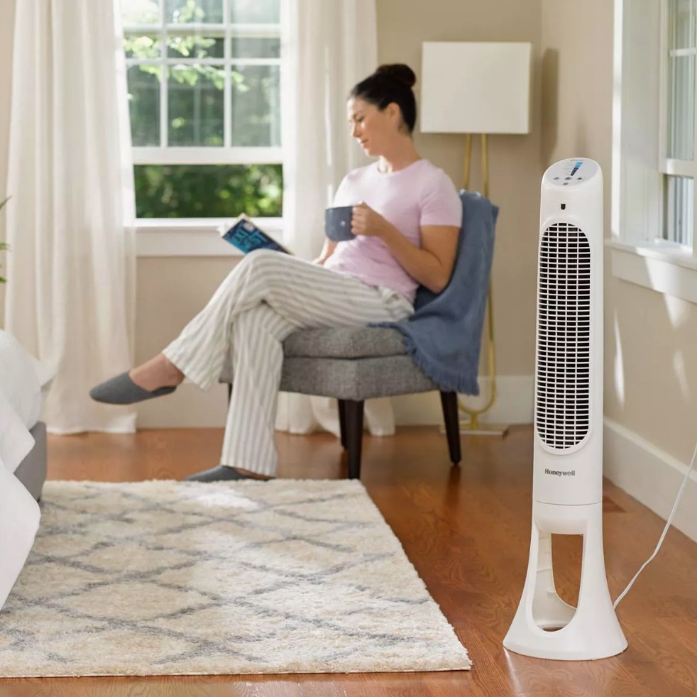 White oscillating tower fan in front of model on chair 