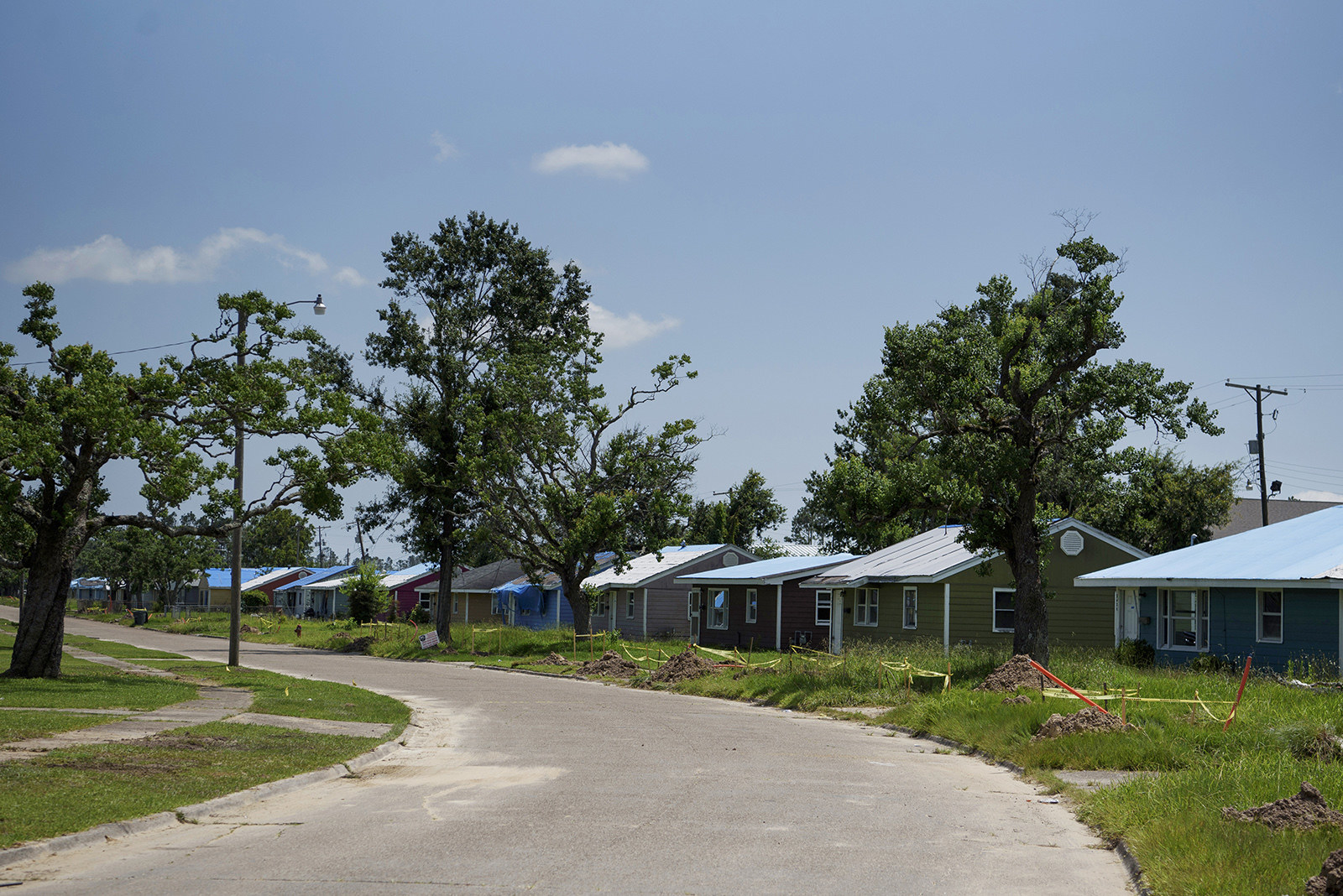 A row of houses, most with blue construction tarps on the roofs 