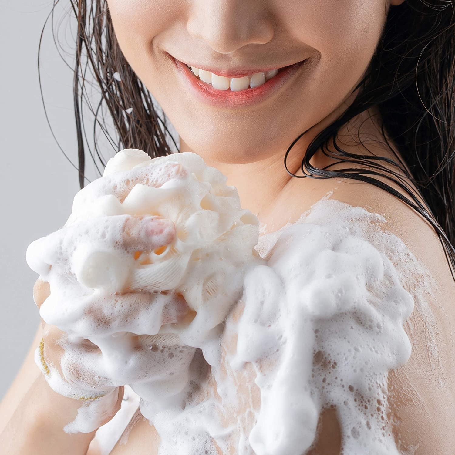 person lathering the wash on their shoulder with a loofah