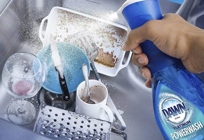 person spraying a pile of dishes
