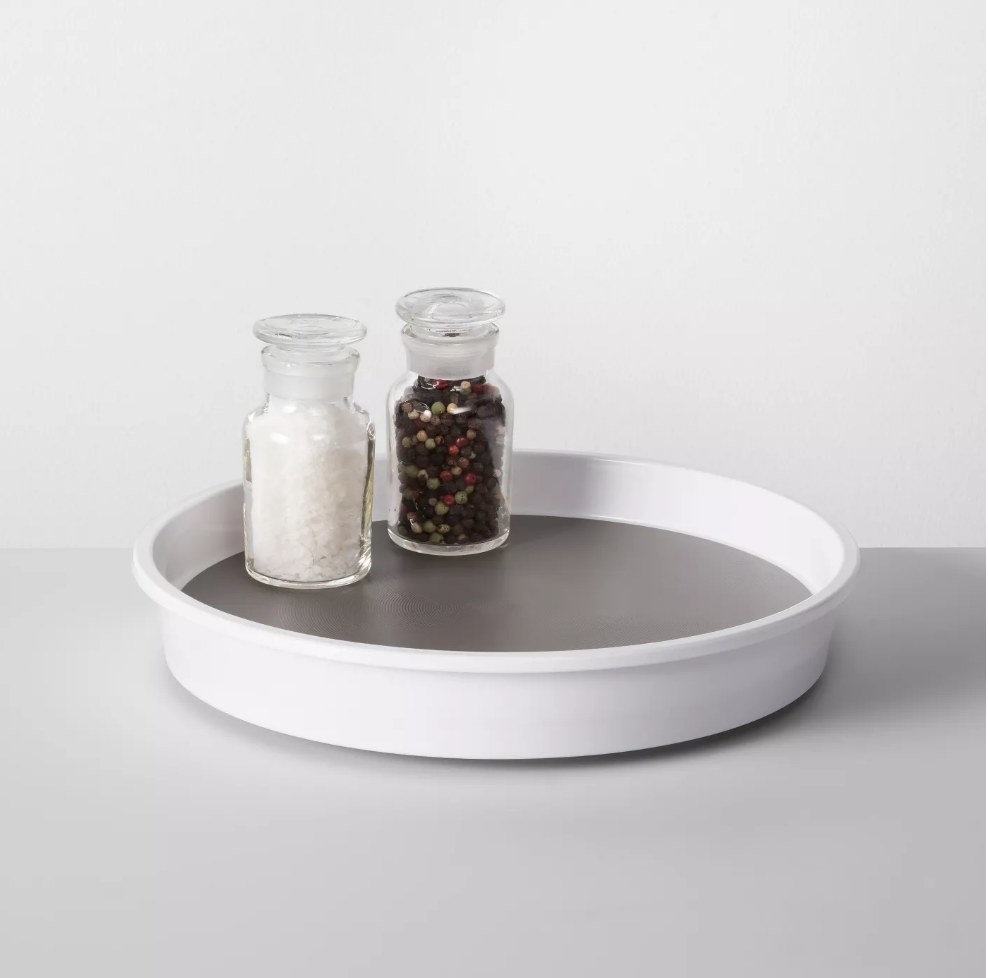 White turn table organizer with salt and pepper shaker in it 