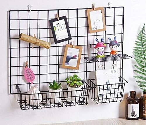 A black grid frame on a wall above a desk with multiple things placed on it.