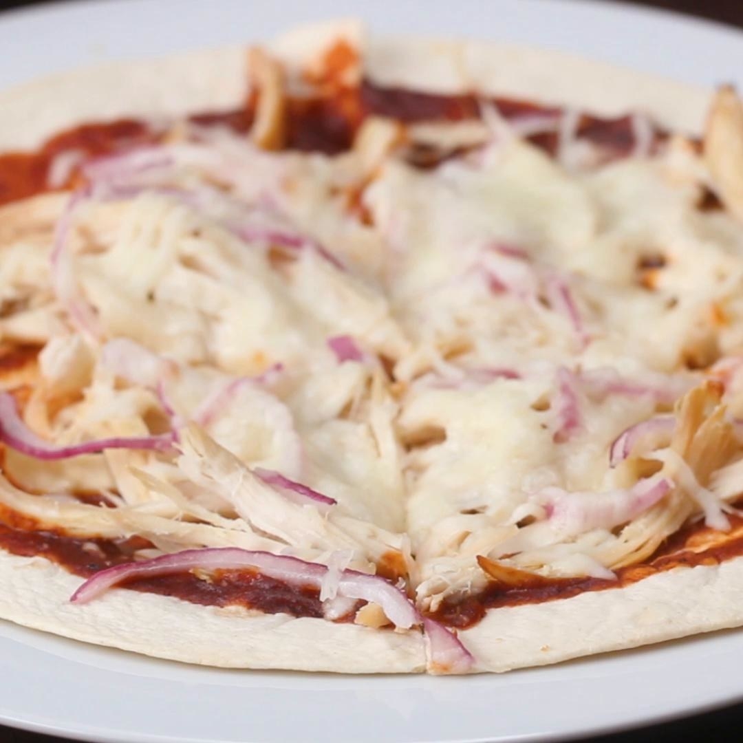 Tortilla topped with chicken, onion, cheese, and sauce