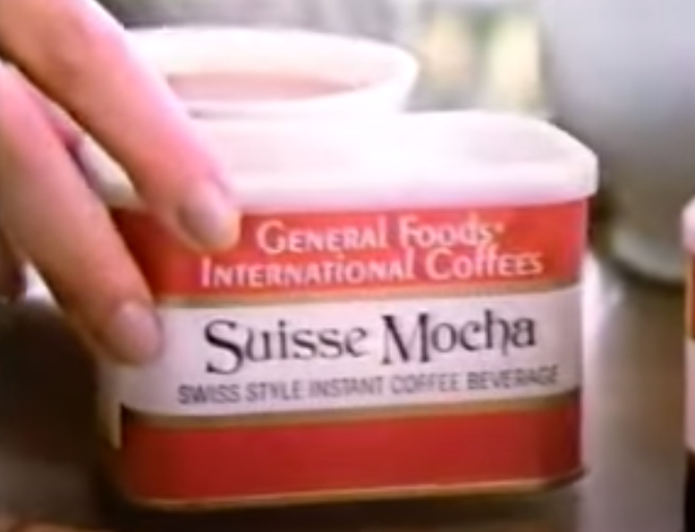 Screenshot of hand holding tin of International Coffee