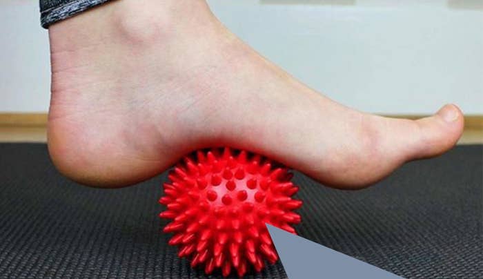 A red spiked ball under a person&#x27;s foot.