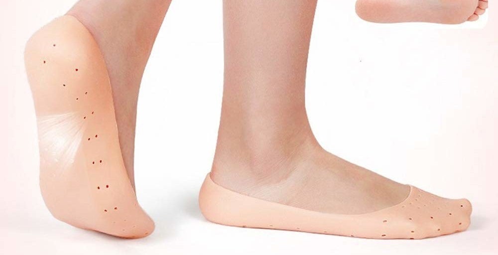 A pair of feet wearing skin-coloured silicone protector socks.