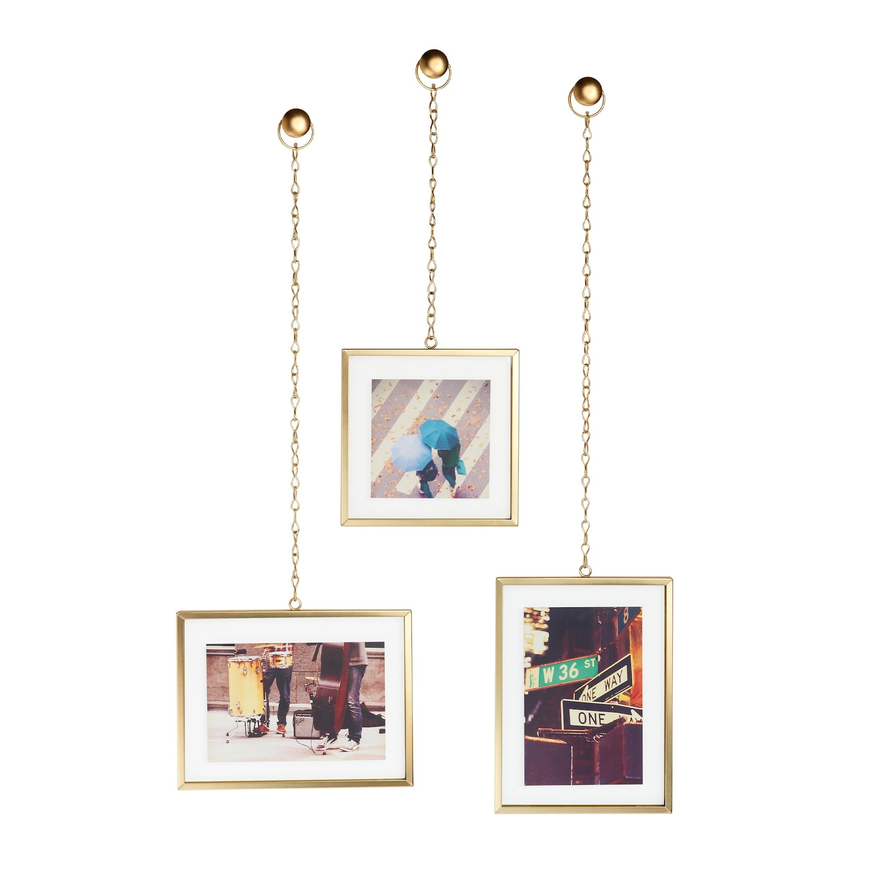 The three photos in gold frames hanging from matching gold knobs mounted to a wall