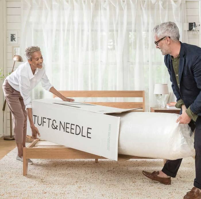 Models removing rolled up mint mattress from box