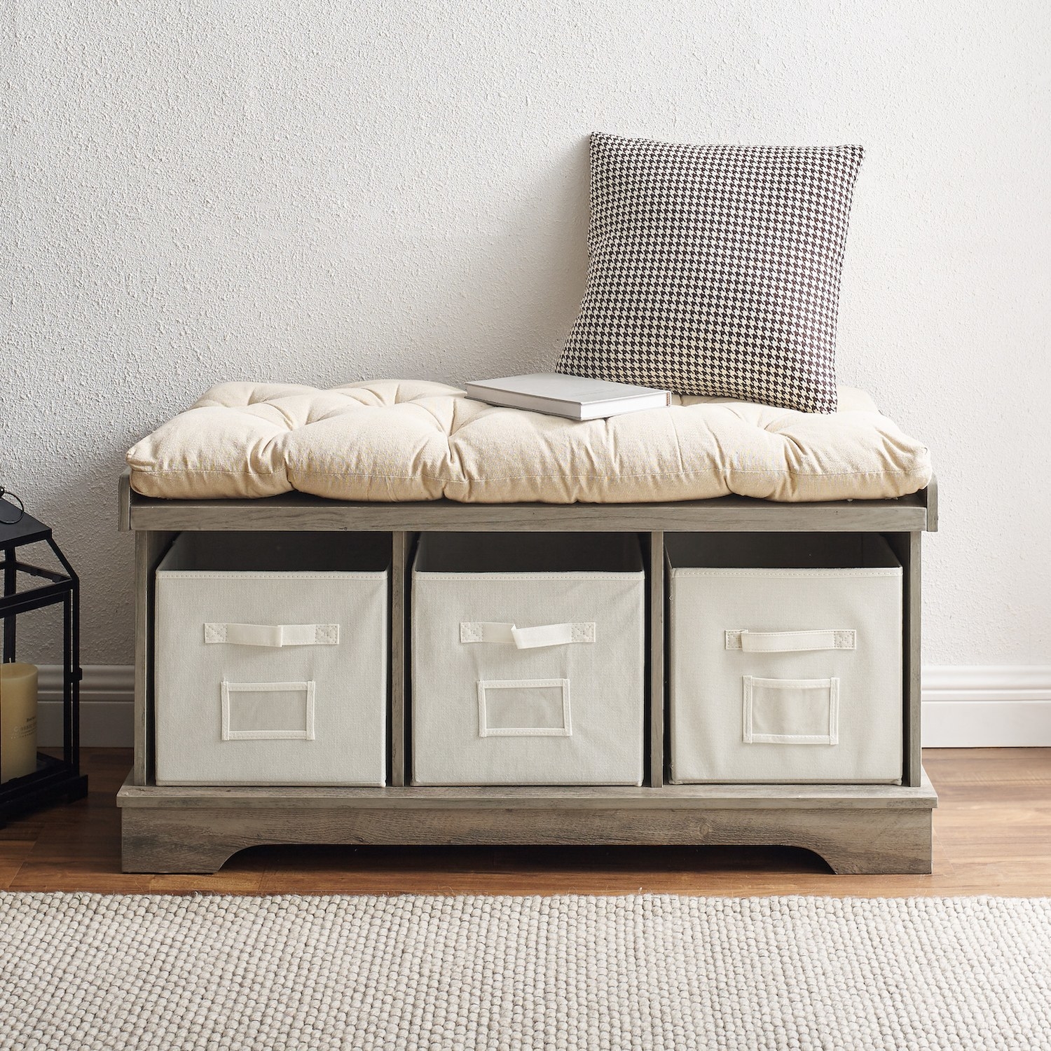 The storage bench with a tufted ivory cushion on top and three matching storage bins underneath