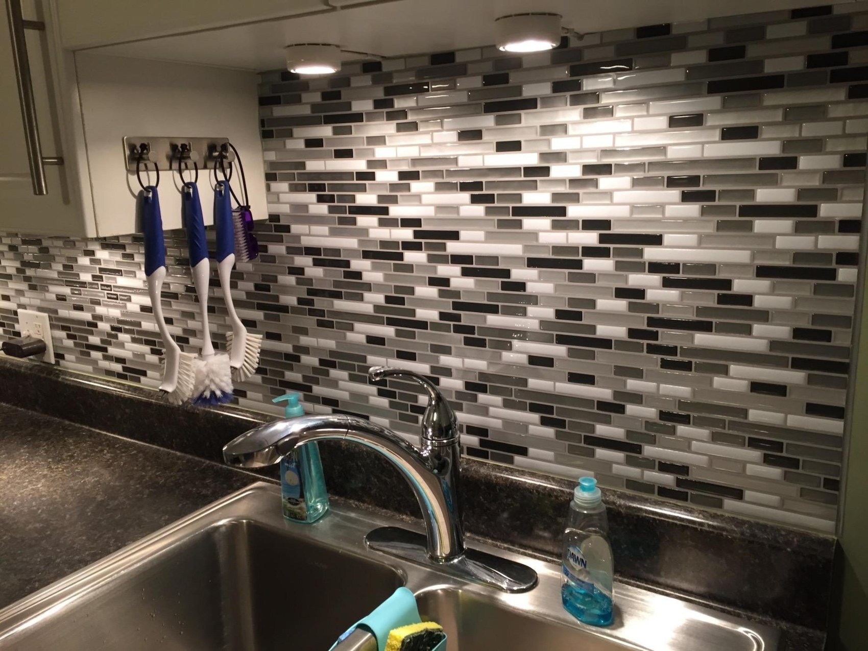 The backsplash with various white, gray, and black rectangles shown on a kitchen wall