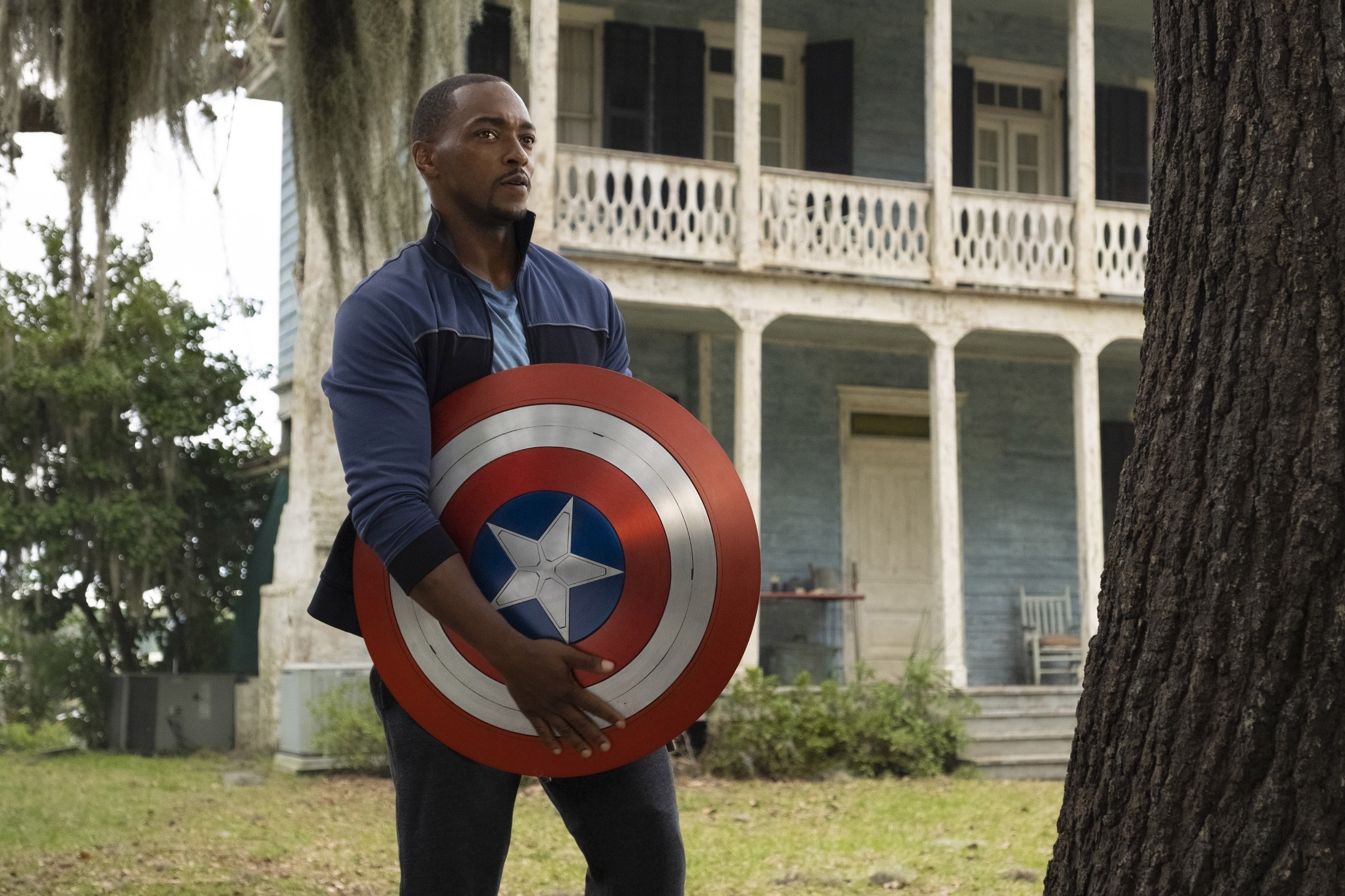 Sam holds the Captain America shield while dressed in plain clothng