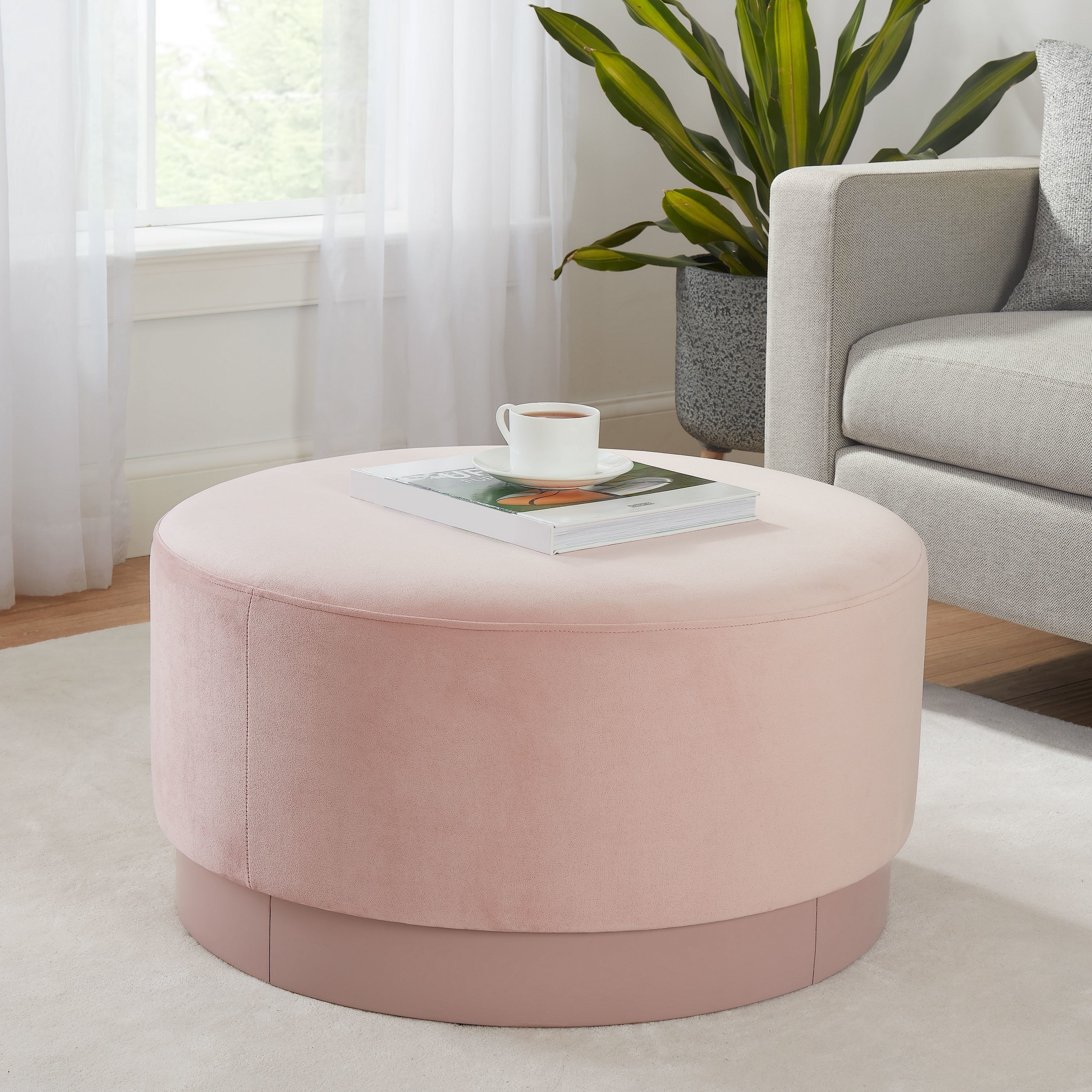 a pink ottoman next to a couch