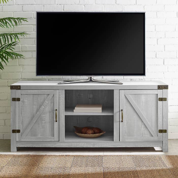 The TV stand with a closed compartment on either side and two open shelves in the middle