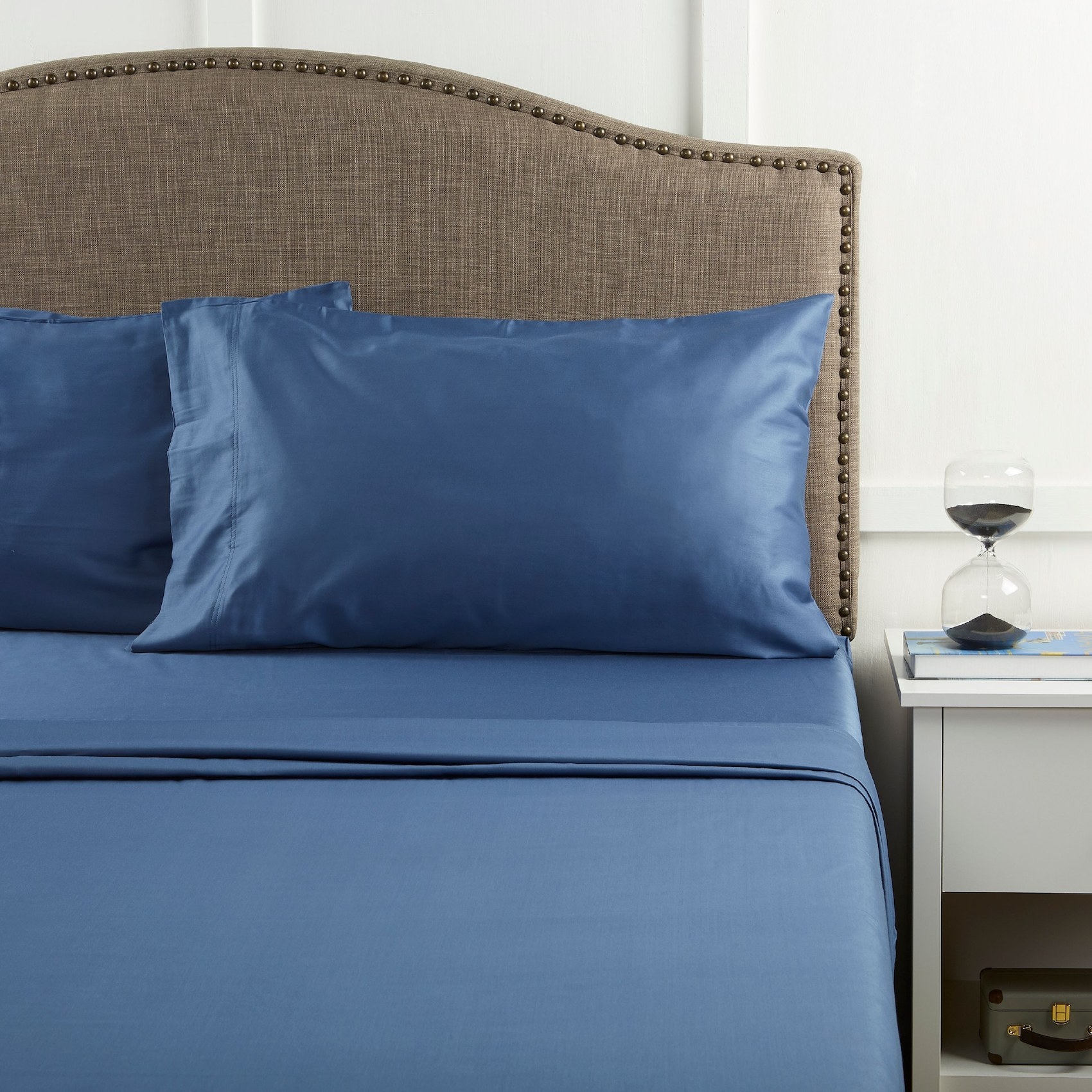 A set of the dark blue sheets with a satin-like finish on a bed