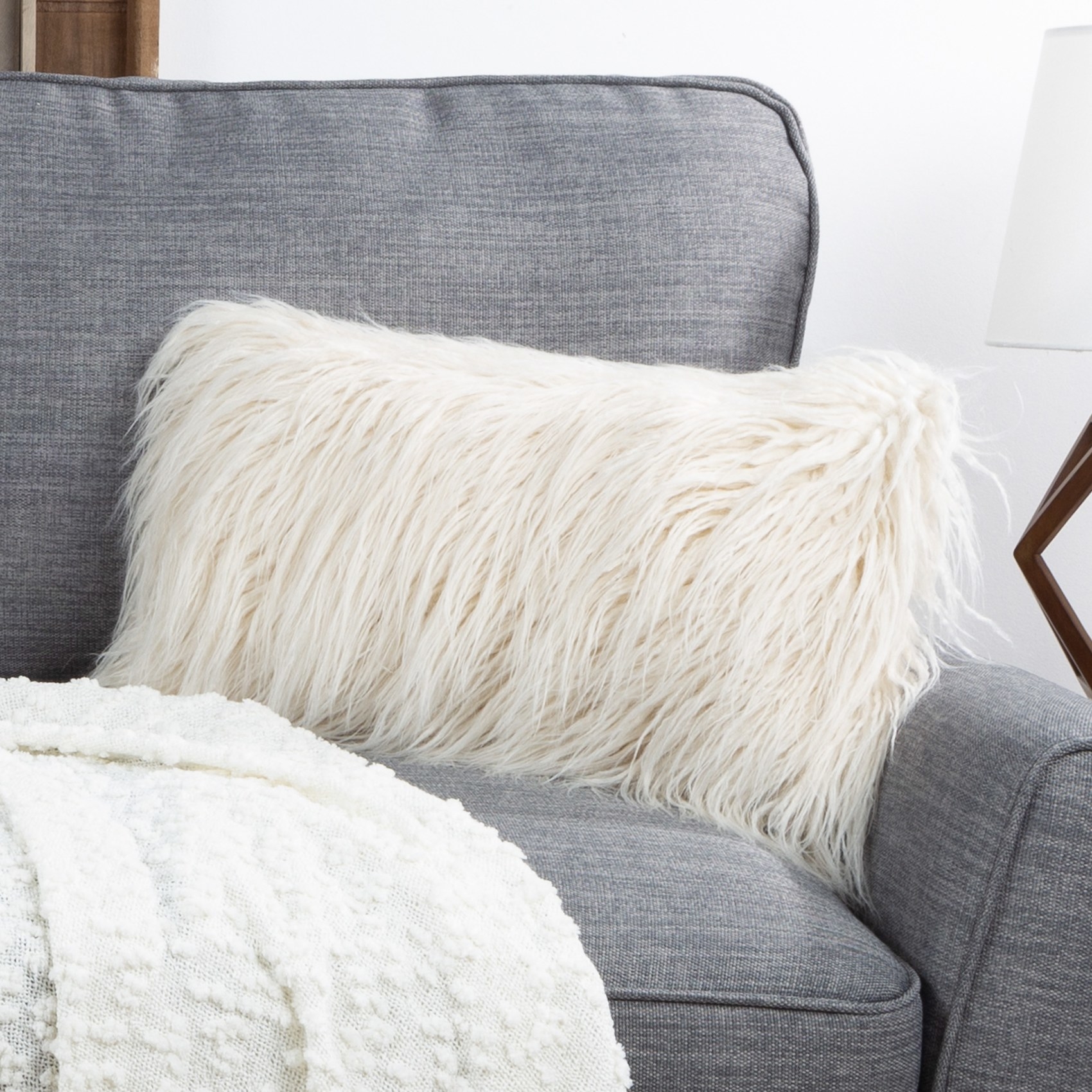 The furry white lumbar pillow on a couch