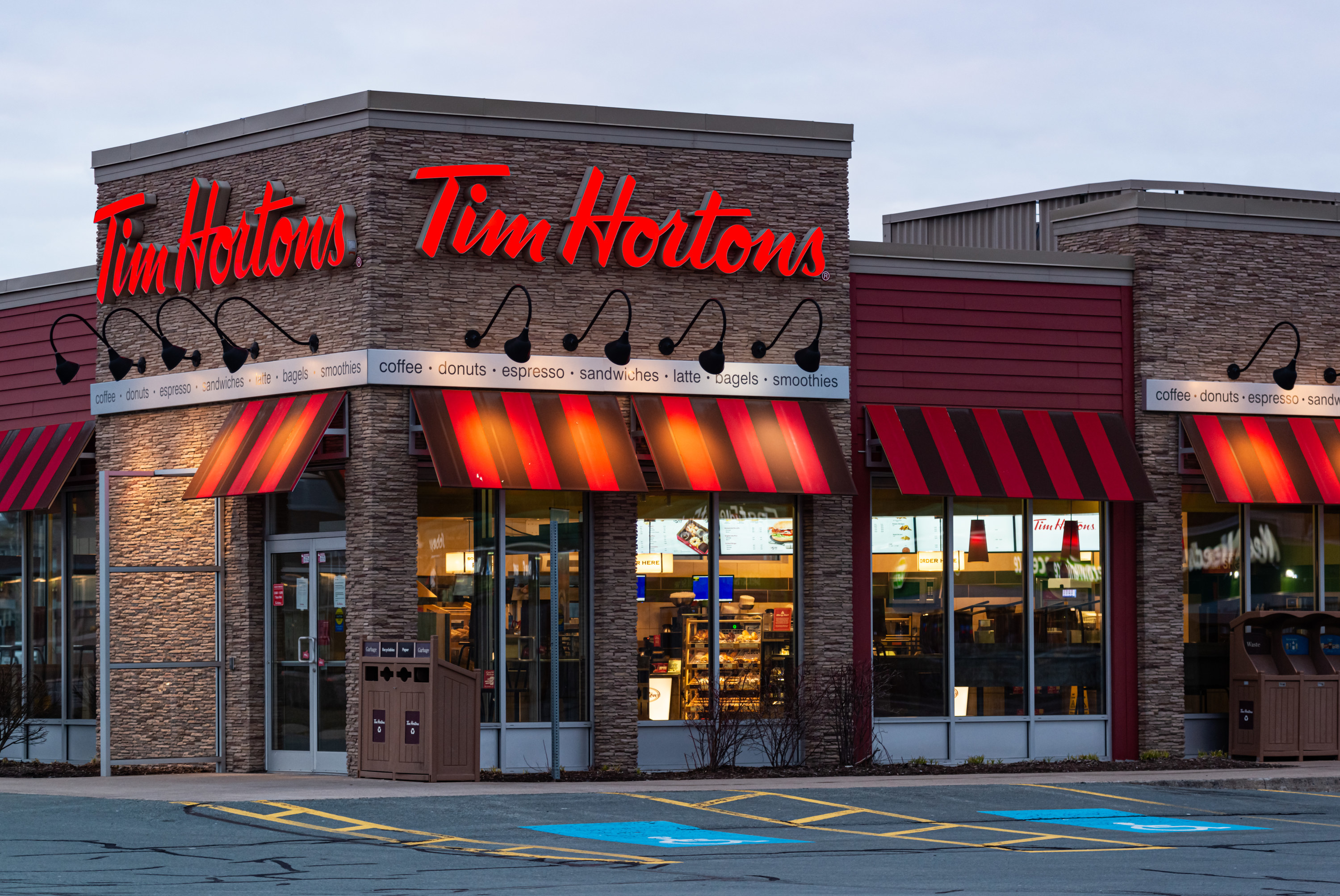 The restaurant chain Tim Hortons building can be seen with a red and black awning. The words "Tim Hortons" are in red.