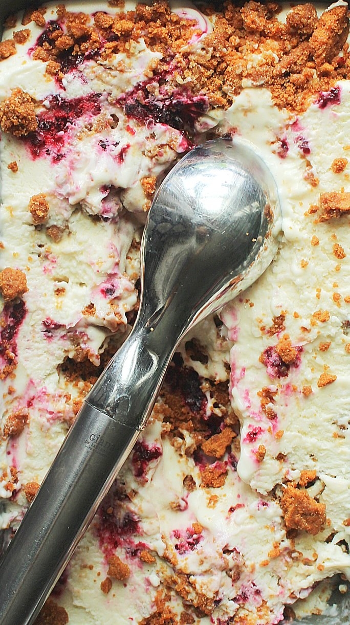 Blueberry Cheesecake Ice Cream with Biscoff cookies crumbled with a silver ice cream scoop.
