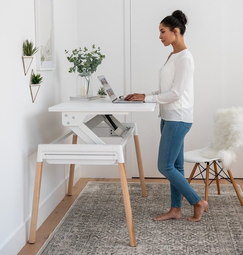 A person standing at a desk working on their laptop