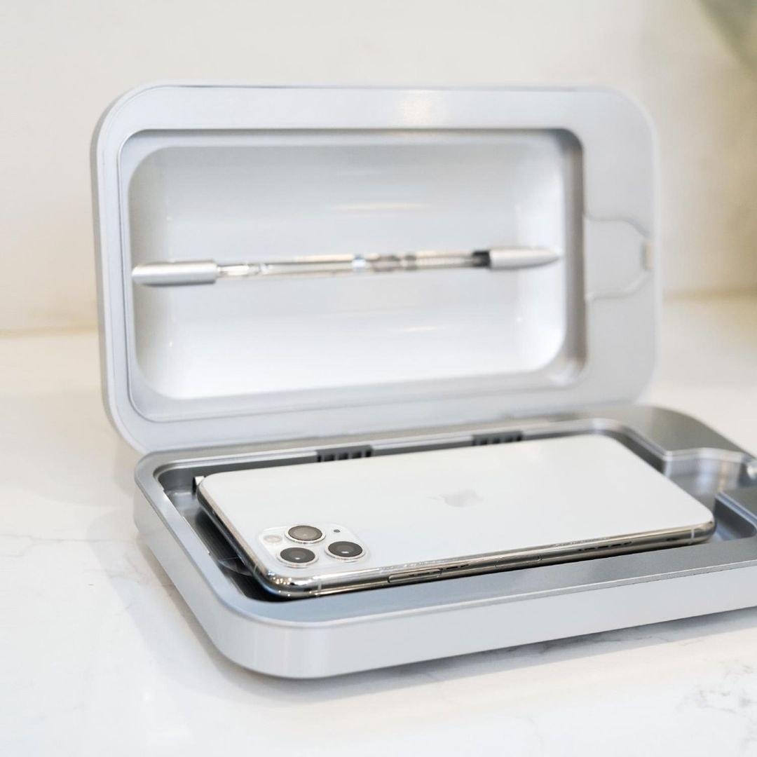 A phone in a small rectangular sanitizing machine