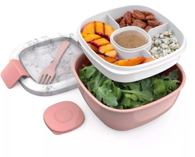 The salad container separated into its components. The bottom bowl contains lettuce, and the top tray is filled with squash, pecans, cheese, and dressing