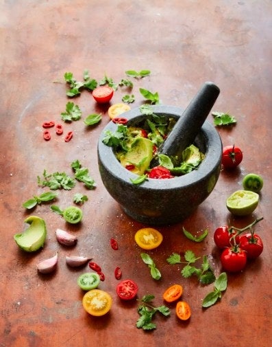 The mortar &amp;amp; pestle being used to grind and mix fresh guacamole