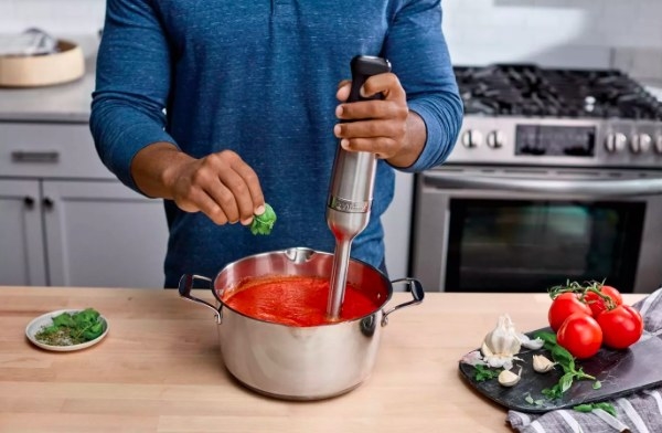 Person making red sauce with the immersion blender