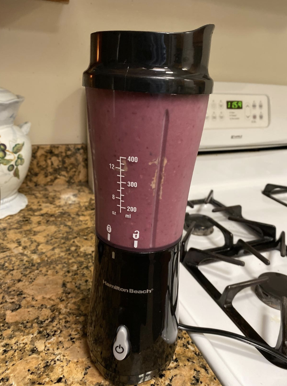 A small blender with a transparent cup full of purple blended fruit 