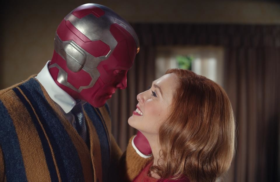 Vision and Wanda Maximoff hold each other, staring directly into each other&#x27;s eyes. Wanda is smiling. 