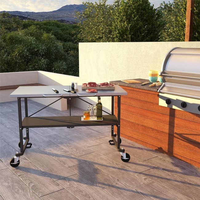 the grill table with two shelves and on four wheels