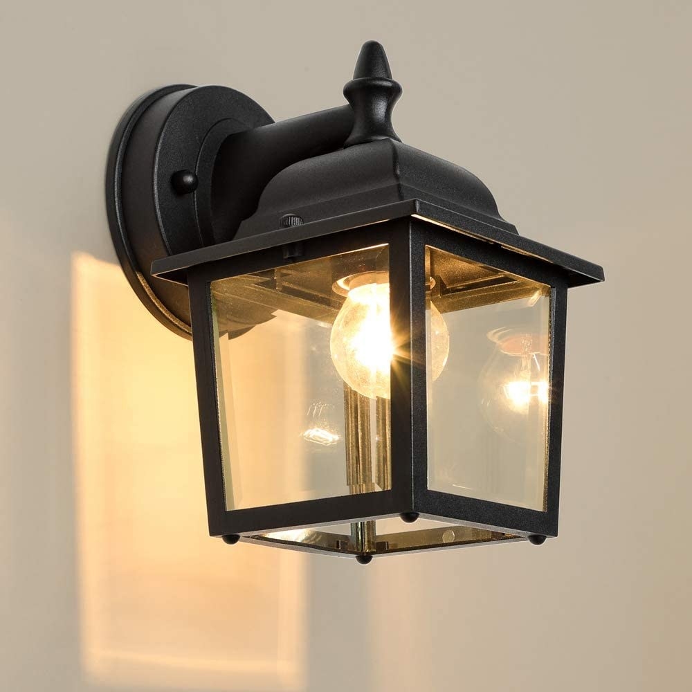 An exterior light sconce on a wall with for glass panels surrounding a light bulb 