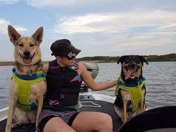 Reviewer and their two dogs wearing green life vests on a boat