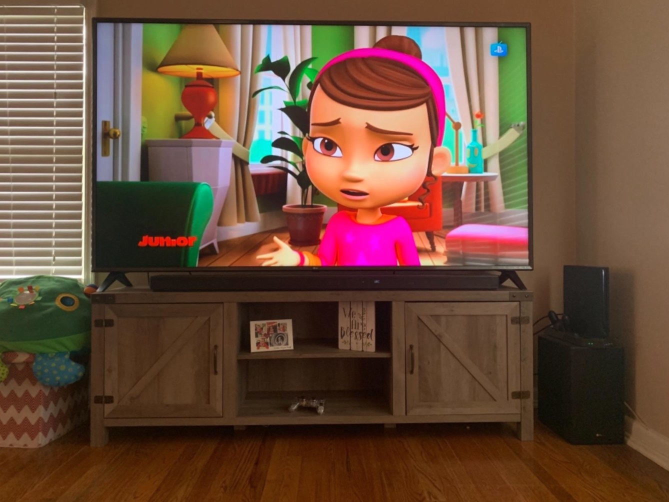 The farmhouse TV stand holding a flat-screen with cartoons on
